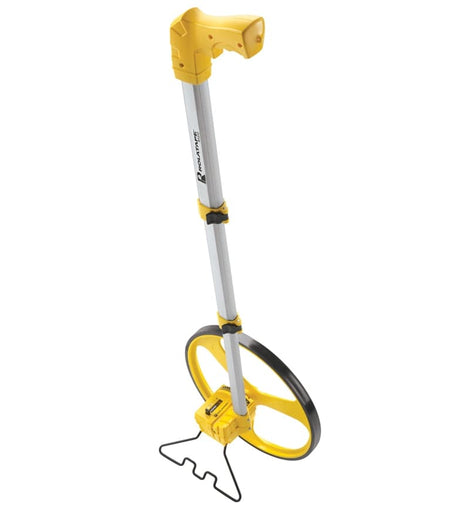 A front-angle view of the Cst/Berger RT312 measuring wheel, showing the yellow spoked wheel, the counter, the telescopic handle, and the black metal kickstand deployed to keep it standing upright.