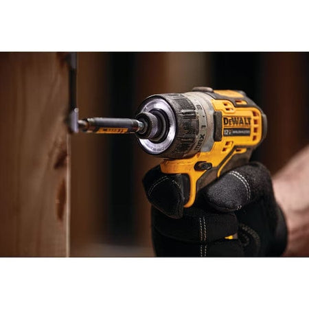 DeWalt drill held by a gloved hand with a blurred wooden background