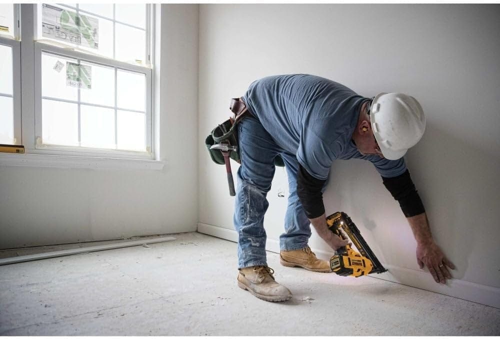 An action shot of a worker using the DeWalt DCN650 finish nailer to install a multi-piece crown molding assembly.