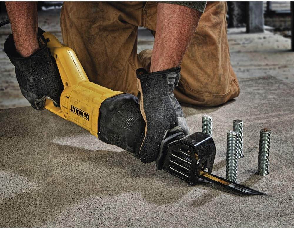 Worker using a DEWALT reciprocating saw to cut a metal rod on a concrete surface, surrounded by upright bolts in a construction or workshop setting.