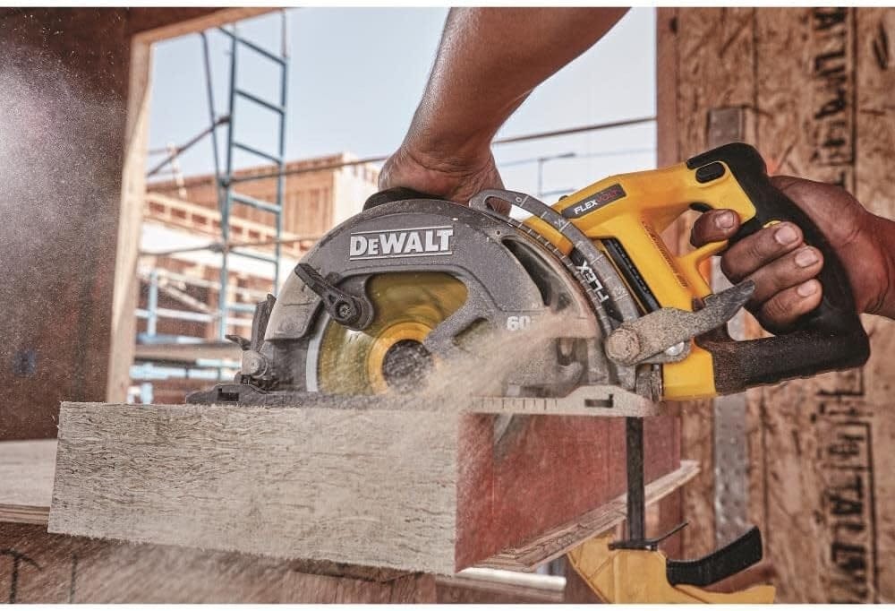 Close-up of a DEWALT cordless circular saw actively cutting wood at a construction site, with sawdust flying and framing materials in the background