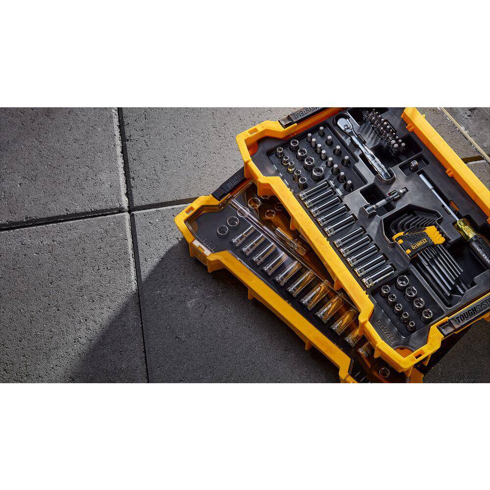 Angled overhead shot of the 131-piece DEWALT mechanics set trays stacked and organized on a jobsite floor, illustrating the comprehensive variety of sockets, ratchets, and fastening accessories included.
