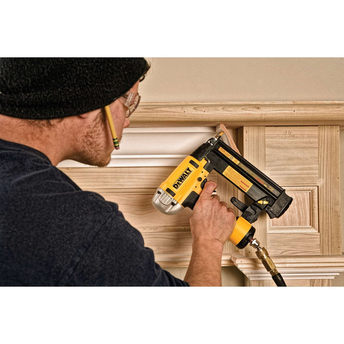 Interior finish application featuring the DEWALT pneumatic brad nailer as a worker installs baseboard trim, demonstrating the accuracy provided by the Precision Point smaller nose design.