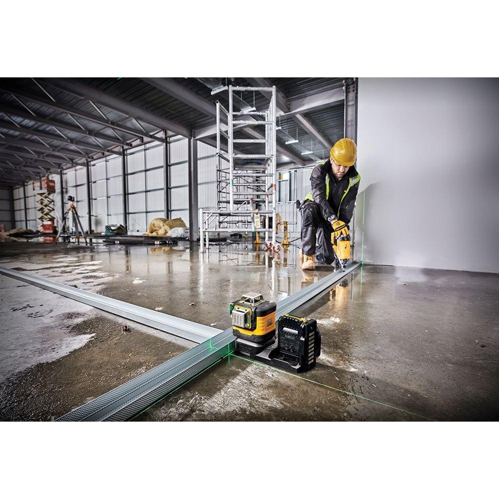 DEWALT DCLE34520G green beam laser level placed on a concrete floor to project long horizontal and vertical lines for aligning metal track during framing.