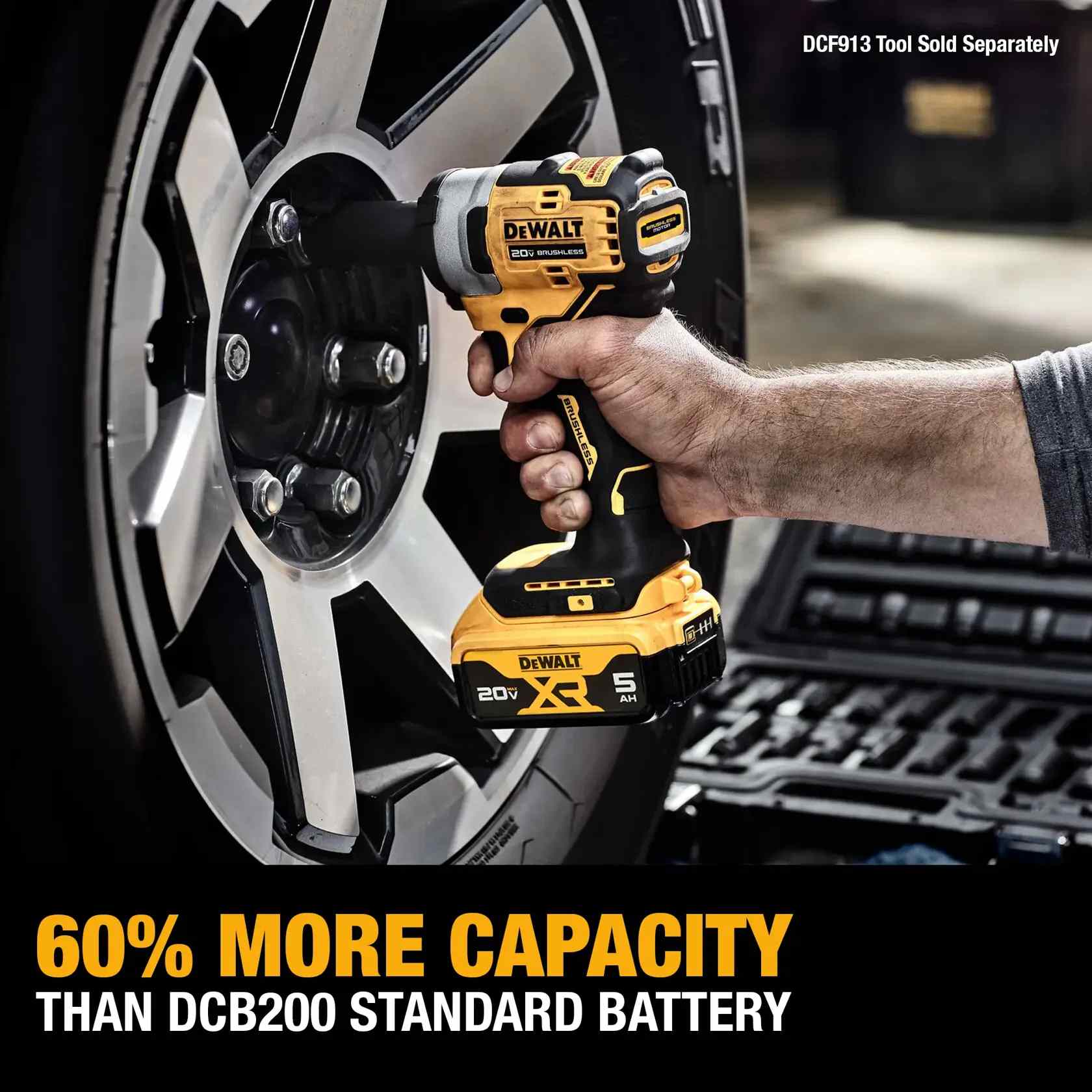 Action shot of a worker using a DEWALT cordless impact wrench powered by a 20V MAX XR 5Ah battery to tighten lug nuts on a vehicle wheel. The image features a text overlay stating 60 percent more capacity than the DCB200 standard battery.