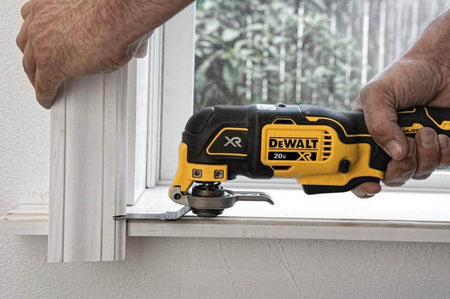 A professional action shot of the DEWALT 20V MAX XR brushless oscillating multi-tool being used to undercut a door casing for flooring installation, demonstrating the multitool's precision and flush-cutting capabilities.