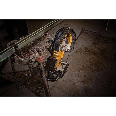 A lifestyle shot of the DEWALT DCS374B portable band saw hanging securely from a jobsite workstation using its integrated hang hook. This view highlights the tool's rugged design and the convenience of the built-in hook for protecting the saw from damage between industrial metal cutting tasks.