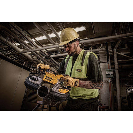 A perspective action shot of a contractor in a mechanical room using the DEWALT cordless band saw. The technician is making a horizontal cut on a heavy-duty steel pipe, demonstrating the saw's balanced weight and the efficiency of the brushless motor during industrial plumbing tasks.