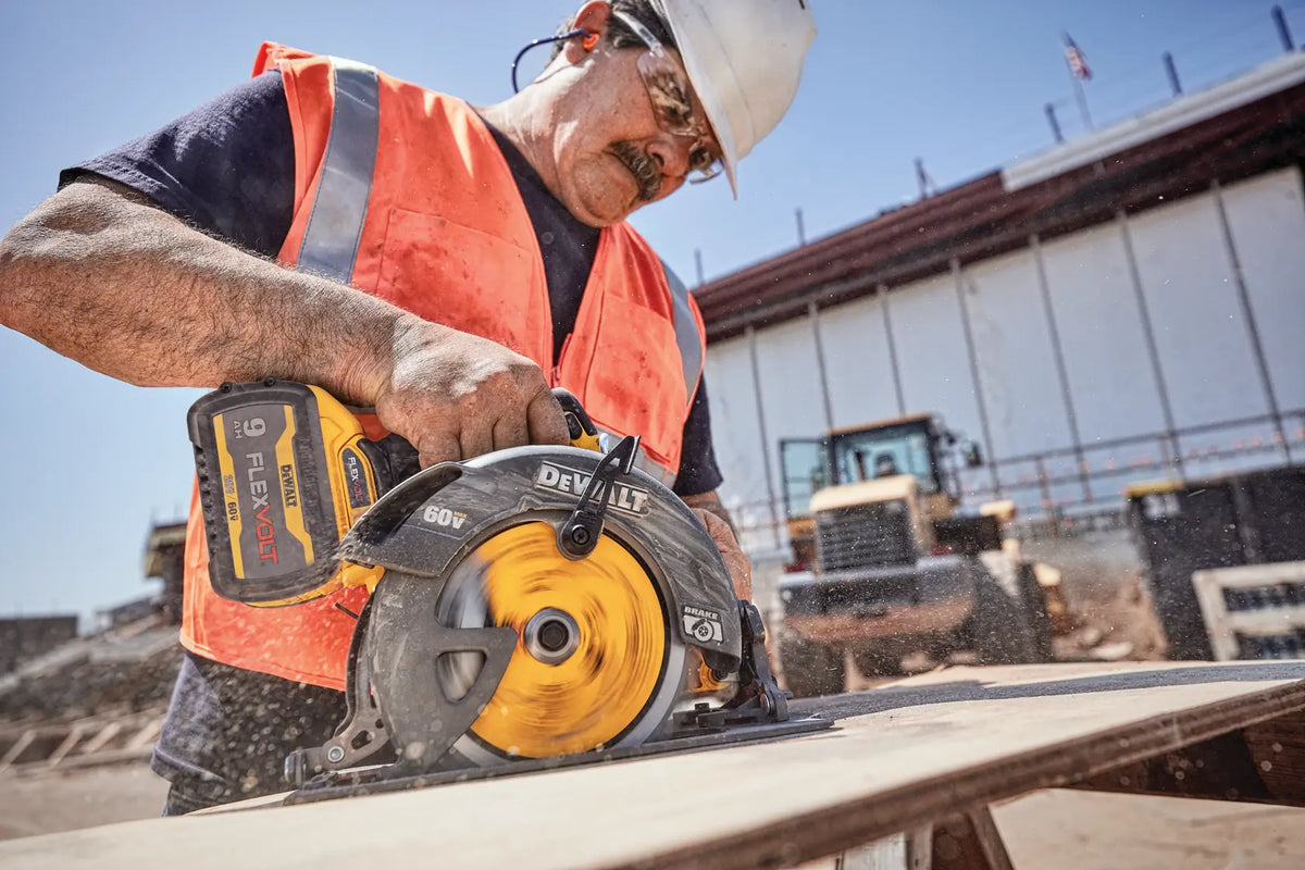 A high-action lifestyle shot of a professional contractor in a safety vest using the DEWALT 60V MAX circular saw to make a rip cut in plywood. The image demonstrates the saw's high-speed brushless motor and cordless portability on an outdoor jobsite.