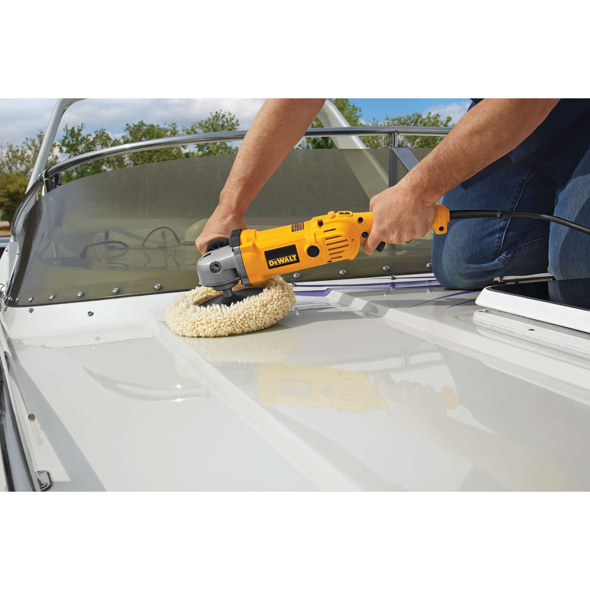 A close-up action shot of a professional using the DEWALT DWP849 7-inch to 9-inch variable speed polisher with a wool bonnet to restore and buff a white marine gelcoat surface on a boat.