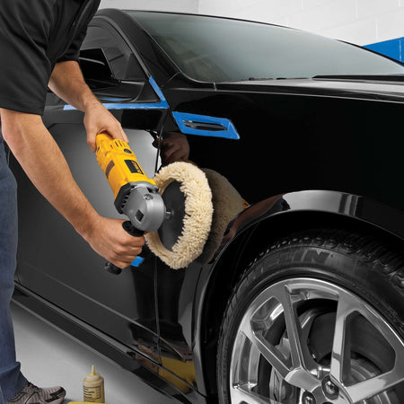 A detailer using the DEWALT DWP849 12-Amp motor corded polisher and a wool buffing pad on a black vehicle fender, demonstrating the precision control required for automotive detailing and finishing.