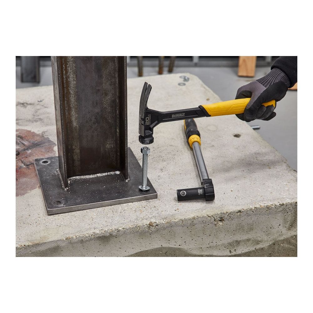 DEWALT 7450SD1 Power-Stud SD1 carbon steel wedge expansion anchor jobsite application view showing a worker using a yellow and black hammer to drive the threaded anchor through a structural steel beam column bracket base plate into a poured concrete foundation pad.
