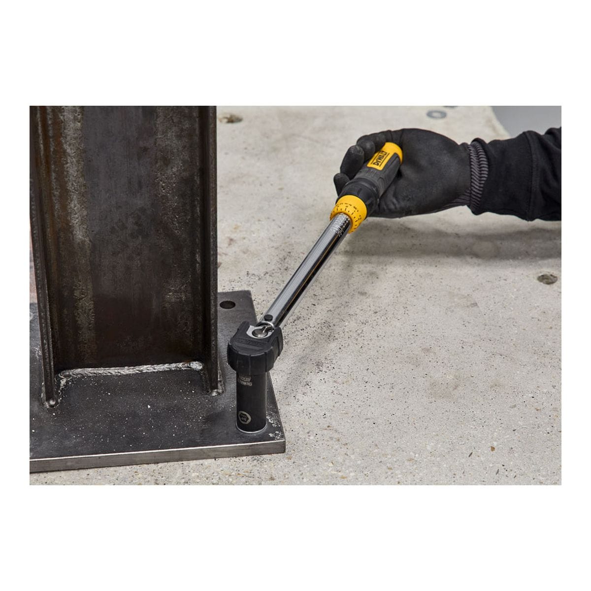 DEWALT 7450SD1 Power-Stud SD1 carbon steel wedge expansion anchor jobsite application view showing a worker using a calibrated mechanical torque wrench tool to tighten the hex nut assembly on the wedge anchor to lock a structural steel column onto a concrete surface slab.