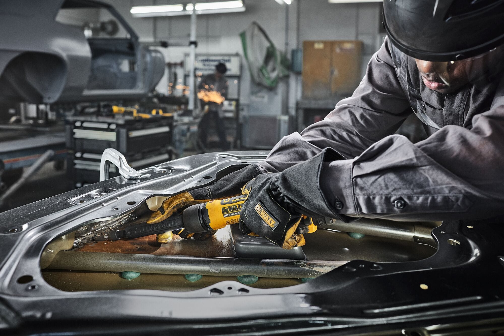 Automotive mechanic utilizing the extended narrow neck of the DEWALT ATOMIC 20V MAX die grinder to grind a recessed weld inside a vehicle door frame.