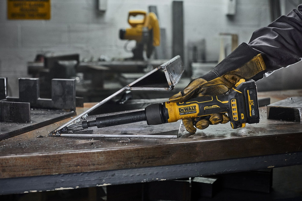 Close-up of a worker operating the DEWALT 20V MAX cordless extended die grinder equipped with a grinding bit to finish an inside corner weld on a steel frame.