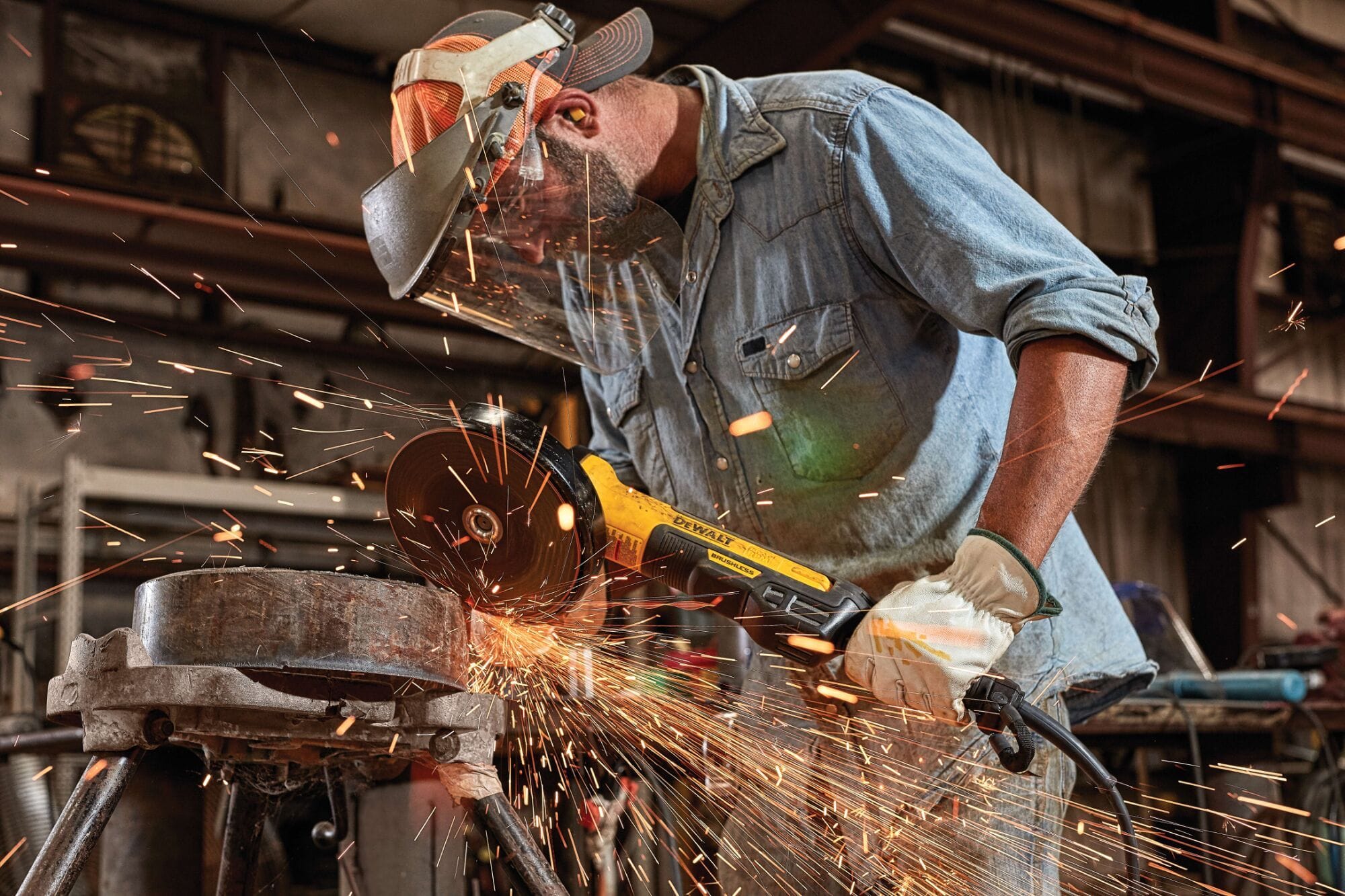 Side view perspective of an industrial worker operating a DEWALT 7 inch 8000 RPM angle grinder tool on a pipeline metal joint workpiece while a dense shower of grinding sparks shoots across a fabrication shop floor.
