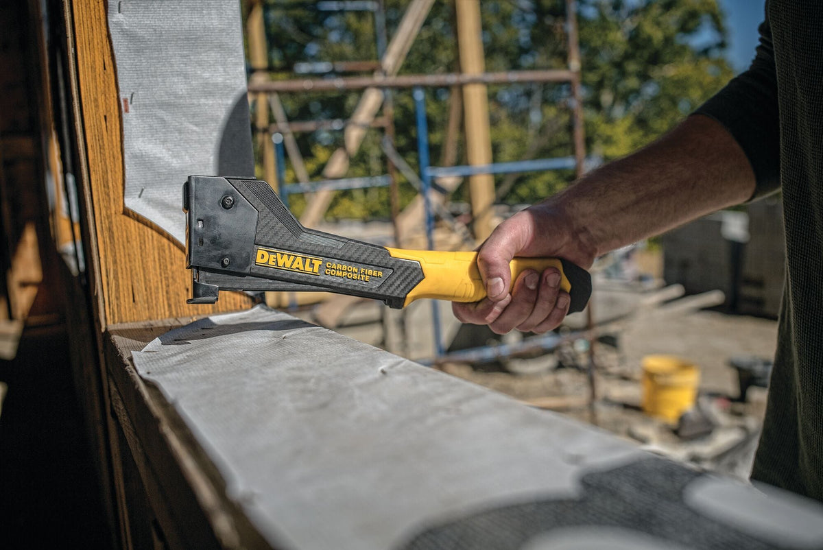 A contractor using the DEWALT carbon fiber hammer tacker to secure weather-resistant house wrap on a residential construction site, demonstrating its easy one-handed operation.