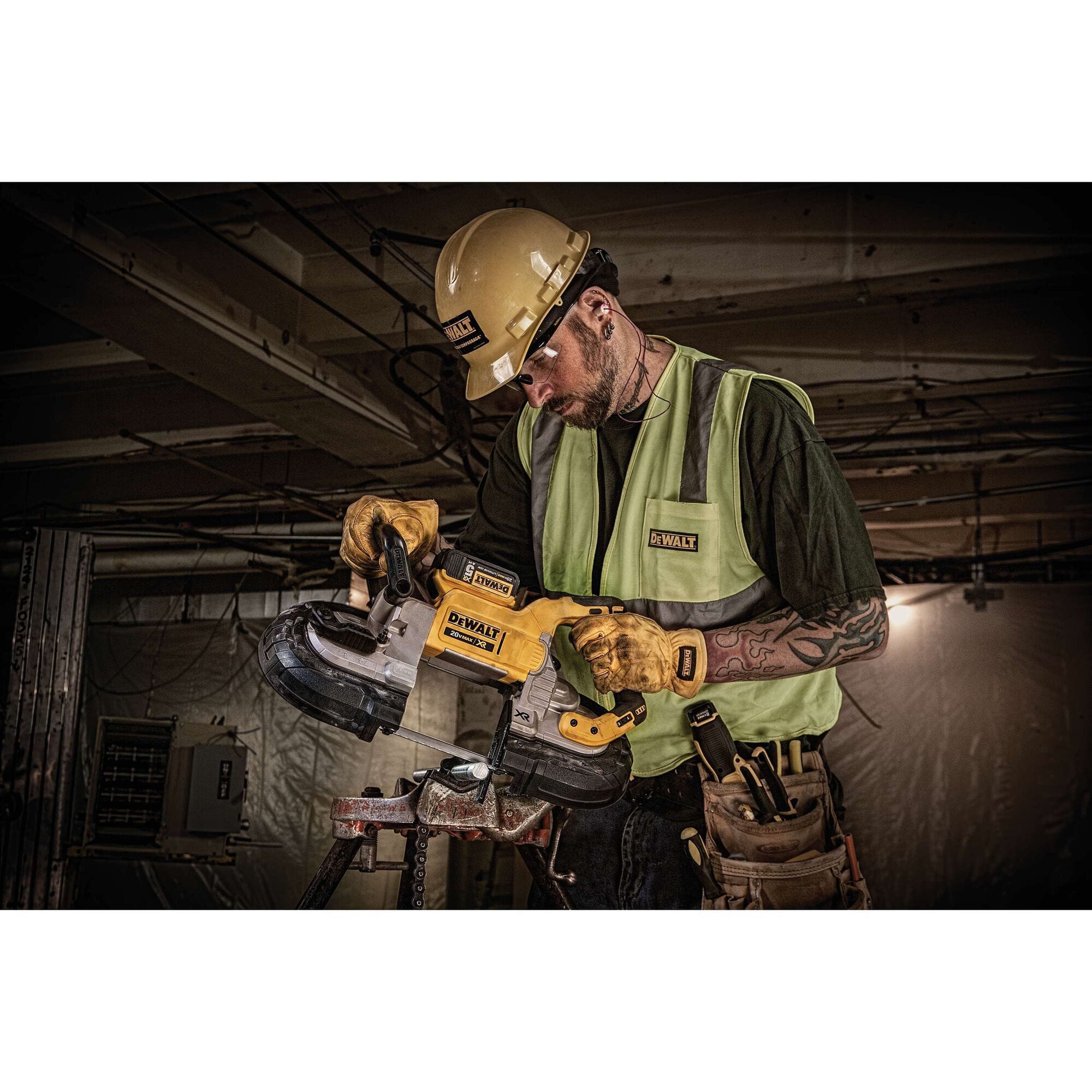 A mechanical professional using the DEWALT DCS374P2 cordless portable bandsaw to cut through a metal threaded rod on a tri-stand vise clamp inside a commercial building utility room