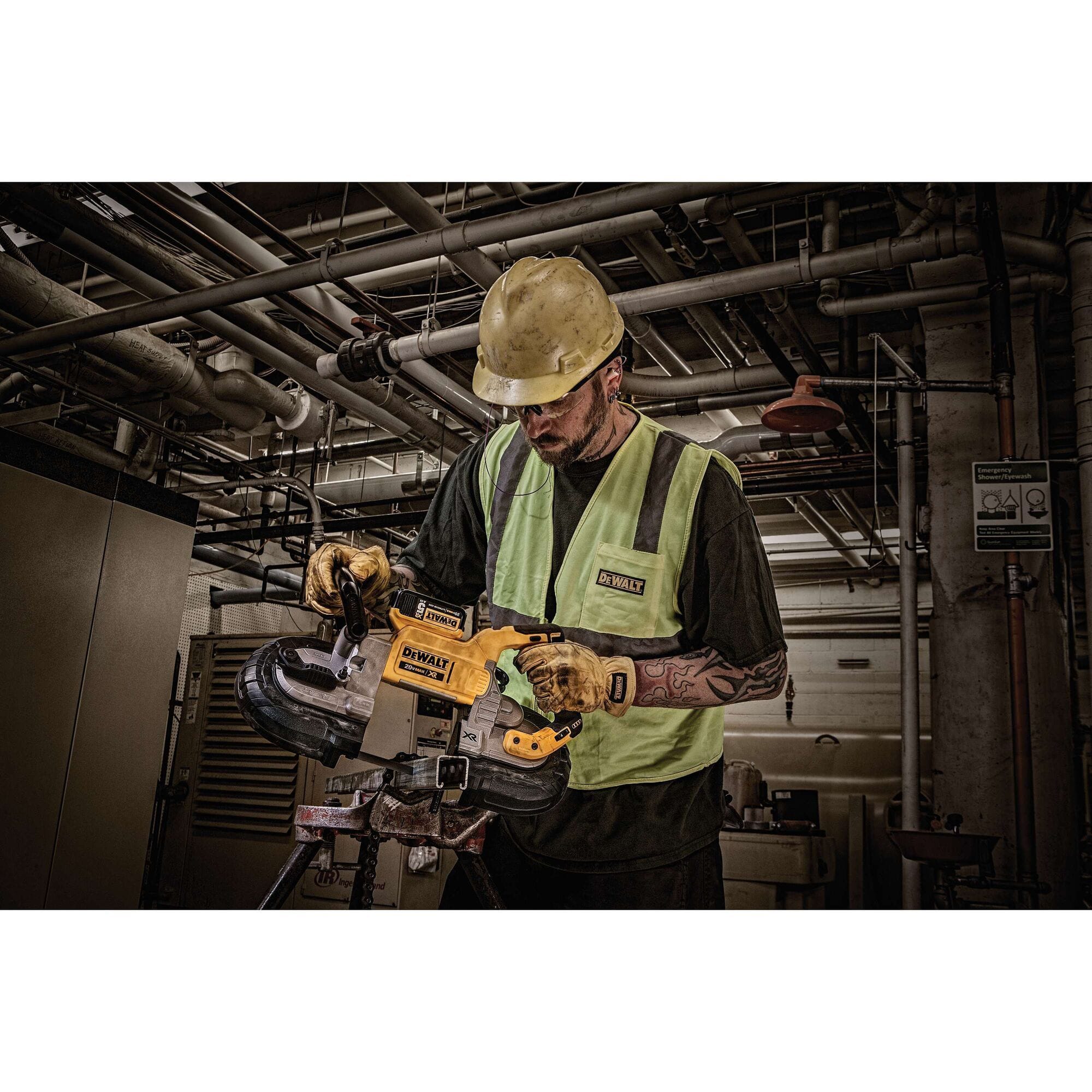 An industrial trade worker in a safety uniform cutting high-strength steel framing materials with the DEWALT DCS374P2 deep cut bandsaw under dim construction site lighting