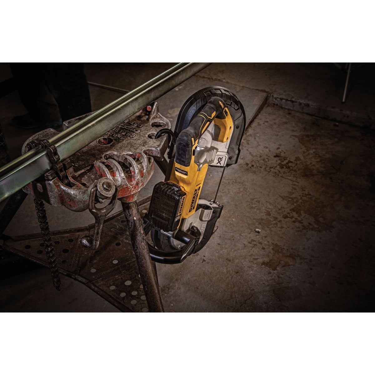 The DEWALT DCS374P2 20V MAX XR cordless portable bandsaw fitted with a 20V battery pack suspended safely by its integrated utility hang hook from a heavy duty pipe chain vise stand