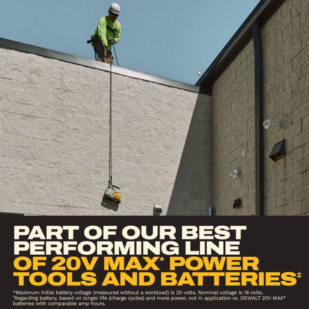 HVAC safety contractor looking down from a concrete block commercial roof edge while lowering or raising the DEWALT 20V MAX XR cordless vacuum pump via a heavy-duty work rope attached to the handle.