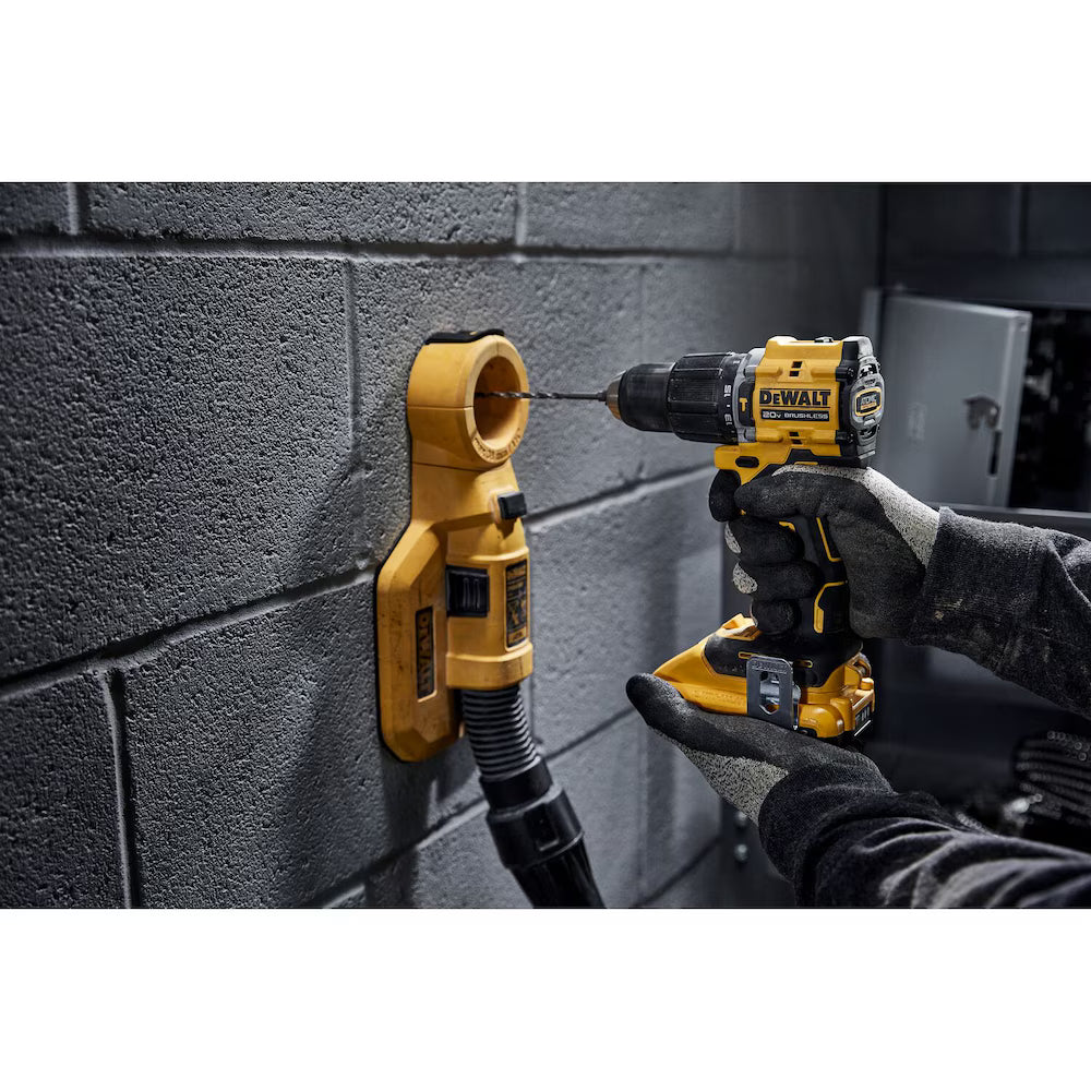 Professional contractor using the DEWALT 20V MAX brushless hammer drill with a dust extraction attachment to drill a precision hole into a grey cinder block masonry wall.