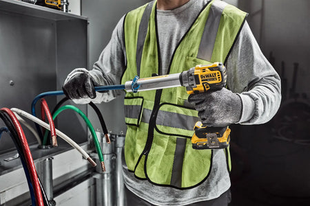 Electrician in high-visibility safety vest using the DEWALT 20V MAX XR brushless cable stripper to quickly strip commercial THHN wire inside a mechanical room.