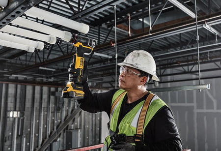 A contractor operating the DEWALT DCE410 cordless PEX expander in a high-reach overhead application, demonstrating the tool's lightweight pro-grade efficiency.