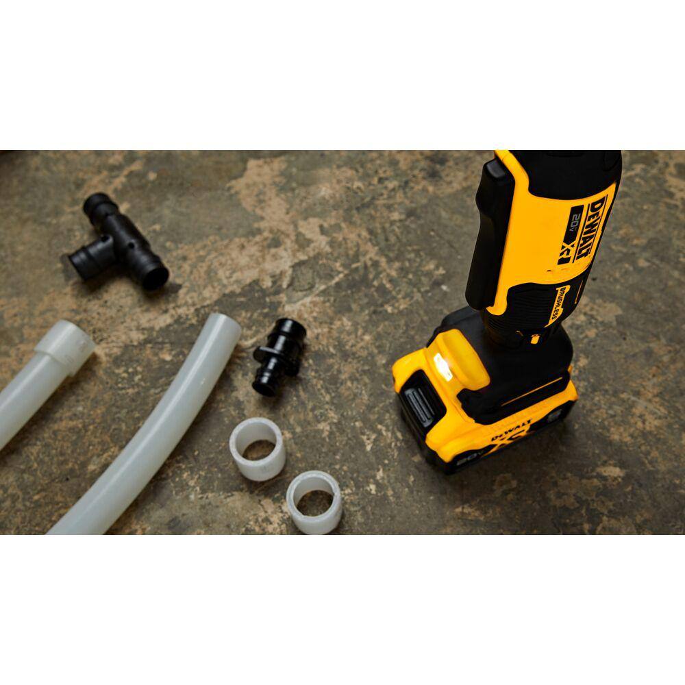 Low-angle view of the base of the DEWALT PEX expander highlighting the bright onboard LED light illuminating plumbing fittings and 1-1/2 inch tubing in a dark work zone.