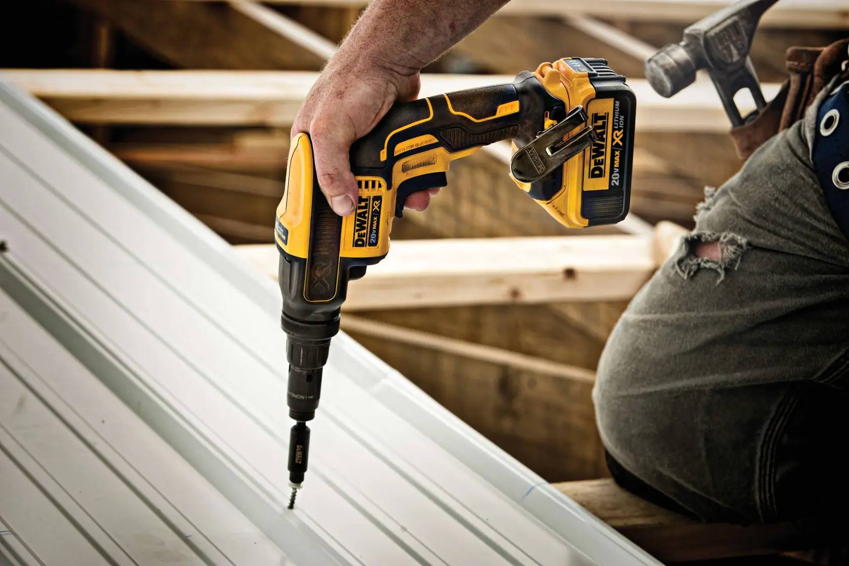 Professional operation of the DEWALT DCF622B screwgun on a construction site, illustrating the tool's portability and ergonomic handle design for all-day metal-to-metal roofing and siding work.