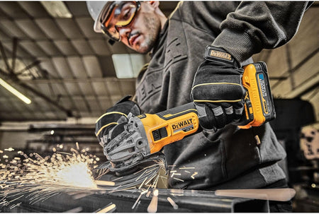 A professional metalworker wearing safety glasses and heavy-duty gloves using the DEWALT 20V MAX XR Brushless angle grinder to cut through a steel beam, demonstrating high-performance spark management and cordless power on the jobsite.