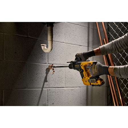 Action shot of the DEWALT XTREME sub-compact rotary hammer being used in a confined space to install a pipe clamp anchor into a masonry wall.
