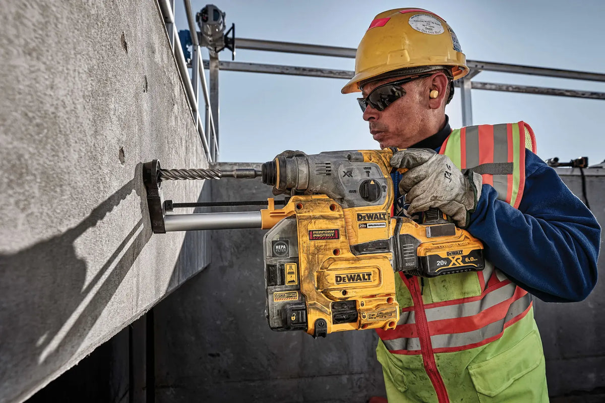 A close-up action photograph of a craftsman drilling into a concrete structure with the DEWALT DCH293B. The high-torque performance is displayed as the tool makes a large-diameter hole, utilizing the 3.5 Joules of impact energy and 1-1/8 inch capacity.