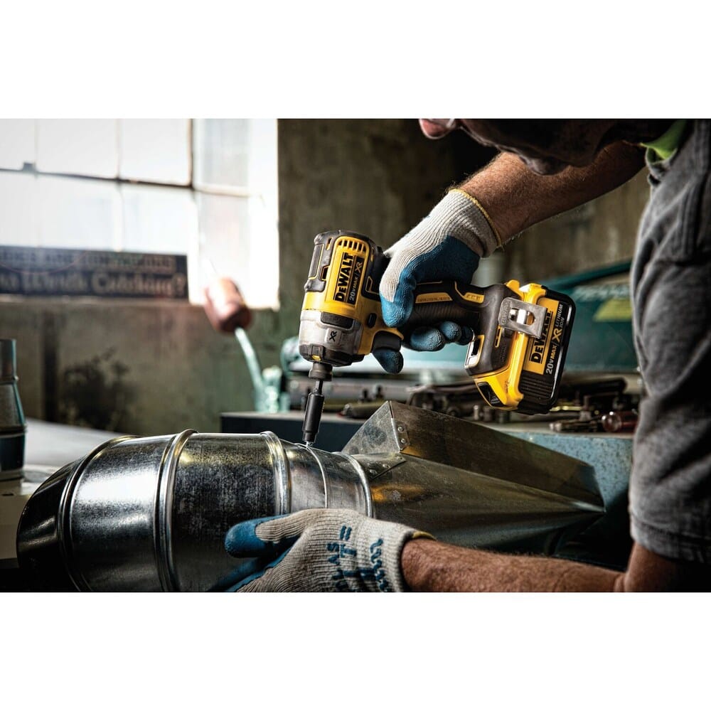 A professional tradesman using the DEWALT 20V MAX impact driver to secure metal ductwork, demonstrating the tool's versatility and power for HVAC and structural applications.