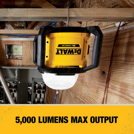 The DEWALT DCL074 5000-lumen work light suspended from a wooden ceiling joist using its integrated heavy-duty hook to provide superior overhead illumination in a mechanical room.