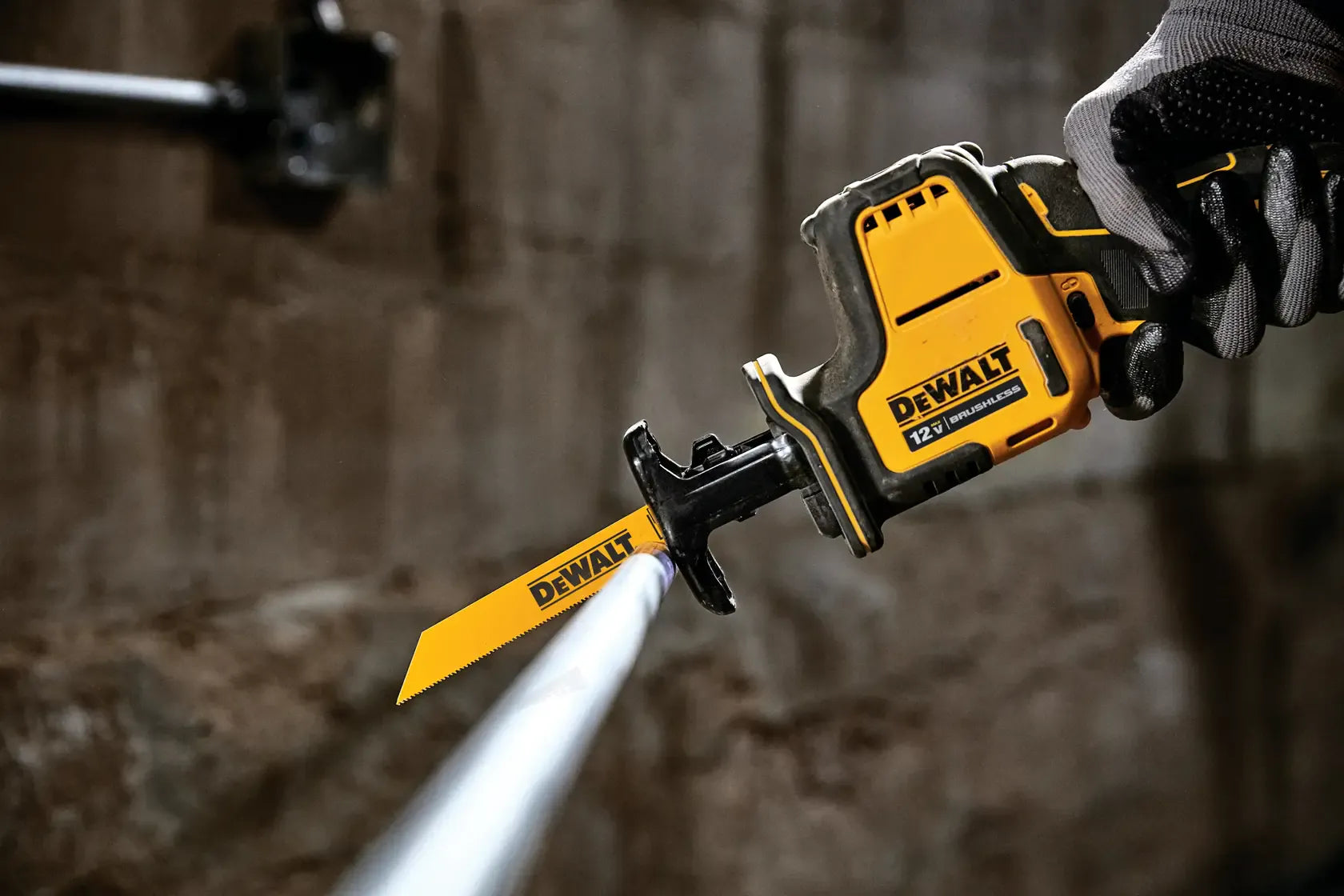 Action close-up of the DEWALT 12V MAX brushless saw cutting through a thin metal pipe, demonstrating one-handed control for plumbing tasks.