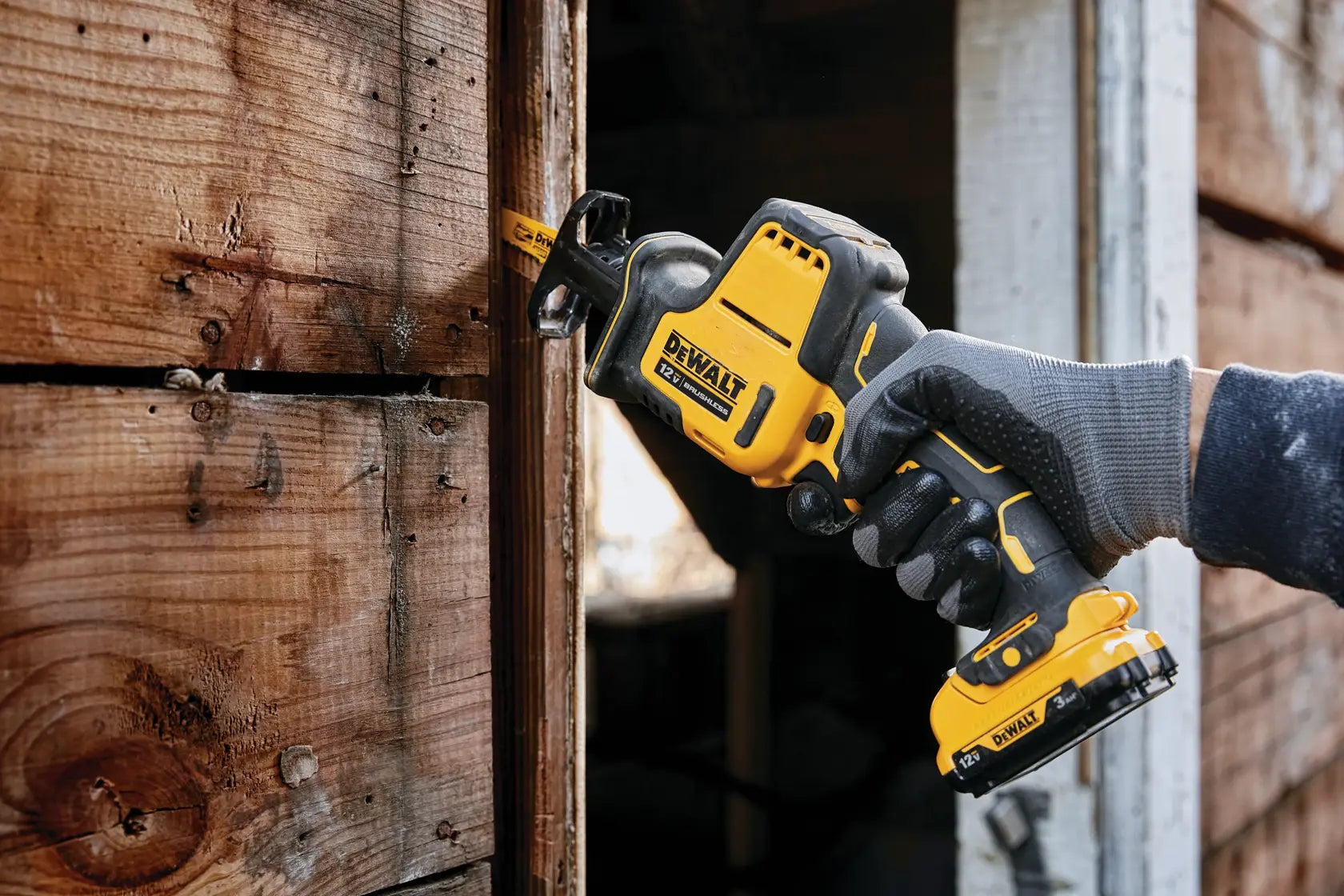 Detailed action shot of a professional using the DEWALT one-handed reciprocating saw to cut PVC plumbing pipe under a sink cabinet, highlighting its compact size.