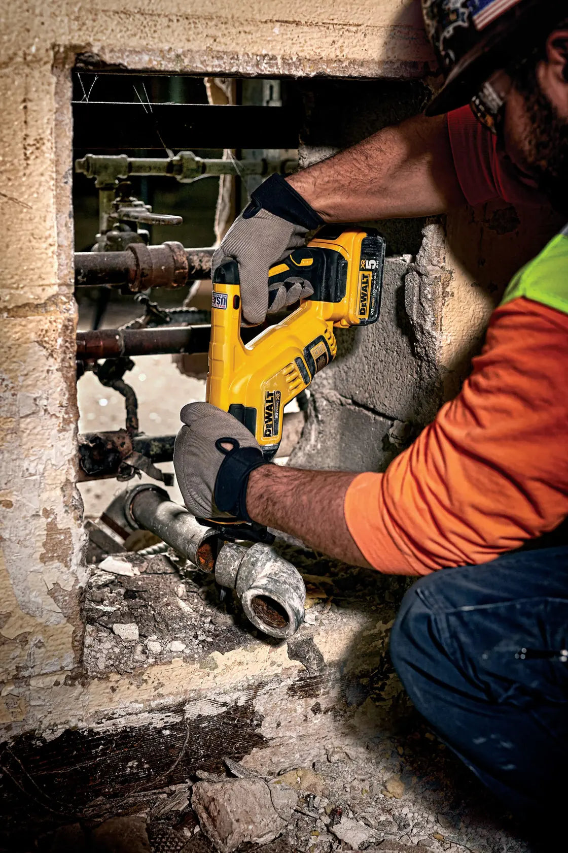 A tradesman using the DEWALT DCS367B to troubleshoot and cut rusted iron pipes within a wall cavity. This lifestyle shot emphasizes the 4-position blade clamp and the compact frame’s ability to perform high-speed metal cutting in restricted demolition areas.