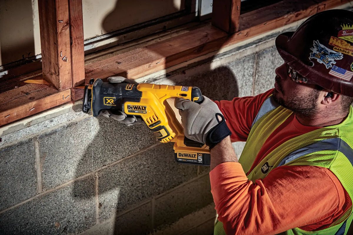 An action photograph showing a technician performing a precision cut through a 2x4 wooden stud. The tool is equipped with a 20V MAX 5Ah battery, demonstrating the high-torque demolition power and visibility provided by the integrated LED work light.