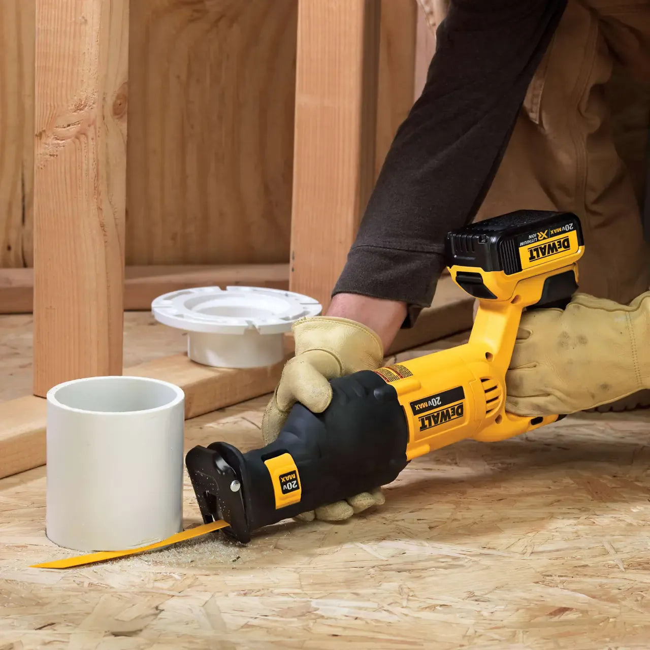 An industrial plumbing tradesman using a DEWALT twenty volt cordless reciprocating saw to execute a clean flush cut on a white PVC plastic drainage pipe structure within a residential building framework.