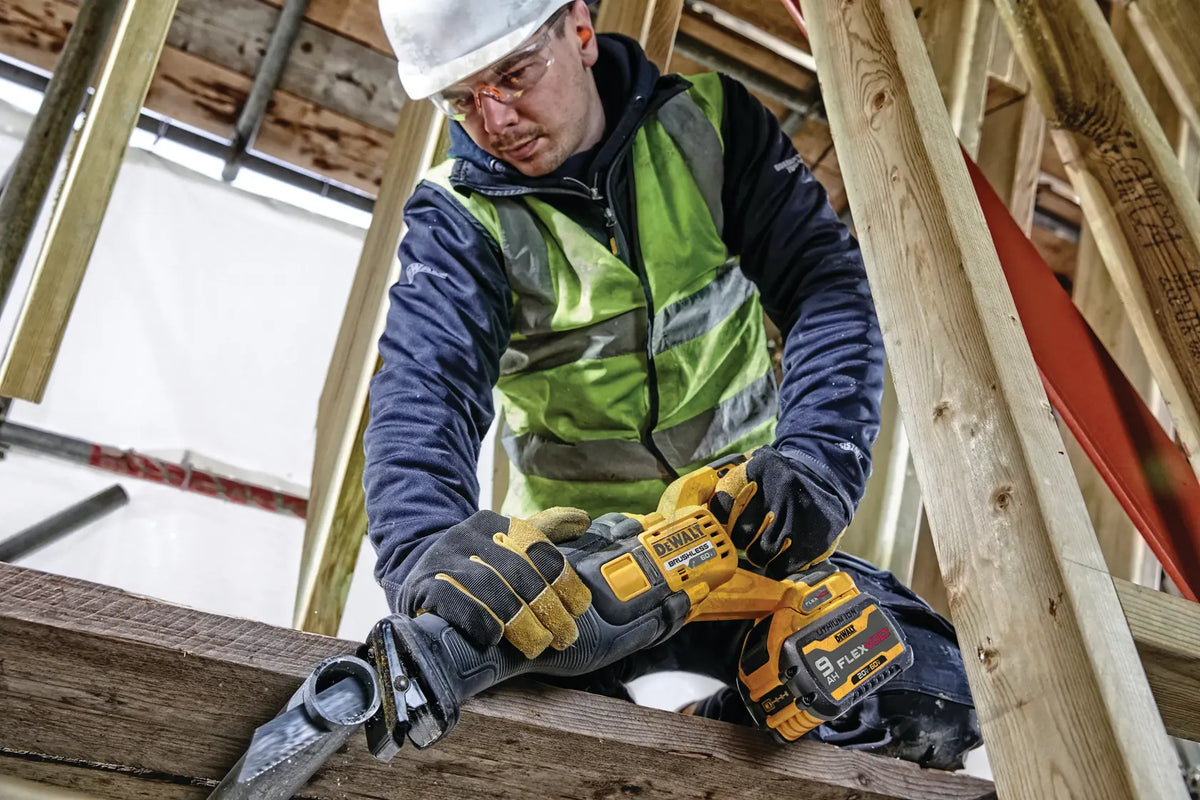 Action shot of a professional tradesman using the DEWALT 60V MAX FLEXVOLT reciprocating saw for overhead pipe cutting in a wooden residential structure. The image showcases the tool's balance and the high visibility provided to the user during precision demolition.
