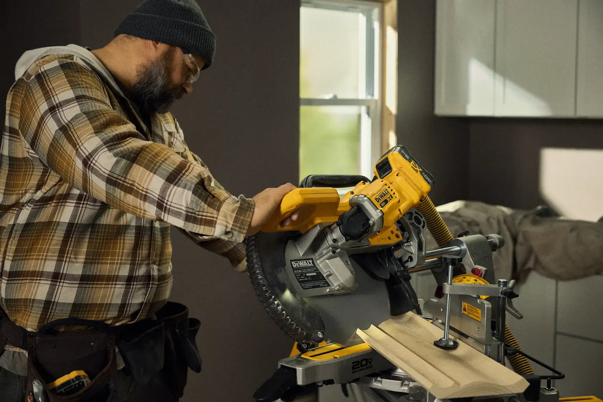 A professional finish carpenter using the DEWALT DCS785B double bevel sliding miter saw to precisely cut decorative crown molding in a residential remodeling project.