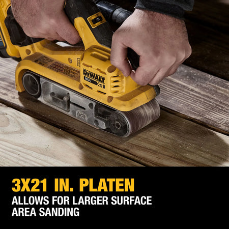 Action shot of a professional using the DEWALT 3x21-inch belt sander on a large wooden workpiece. The caption 3x21 IN. PLATEN ALLOWS FOR LARGER SURFACE AREA SANDING emphasizes the tool's efficiency in rapid material removal and leveling tasks.