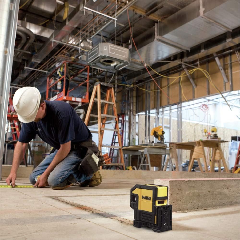A professional contractor on a jobsite using the DEWALT DW0851 Spot and Line Laser placed on a concrete floor to guide the accurate measurement and placement of interior wall structures.