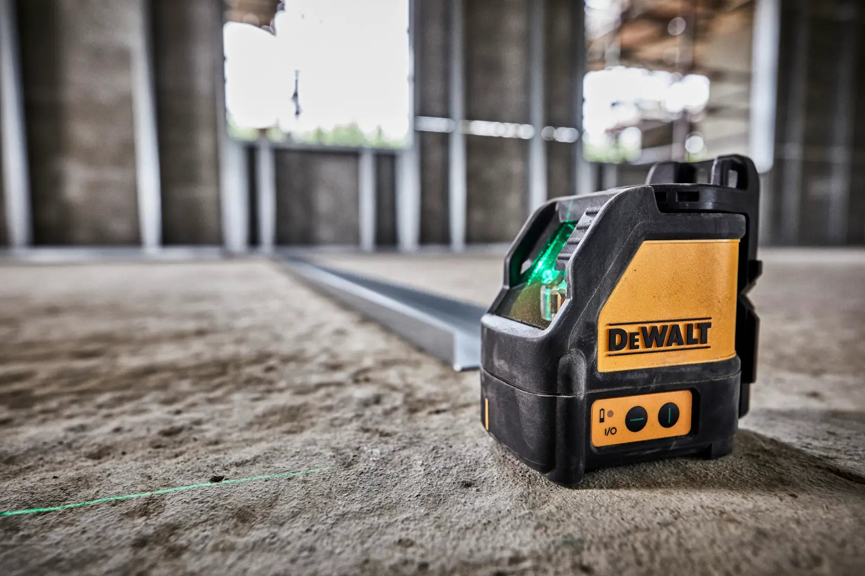 Low-angle view of the DEWALT green beam laser level in an active construction zone, demonstrating its ability to project sharp leveling lines across large interior spaces for professional trades.