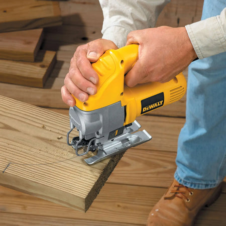 Action shot demonstrating the DEWALT heavy duty jig saw performing a curved scroll cut on a piece of dimensional lumber at a construction site.