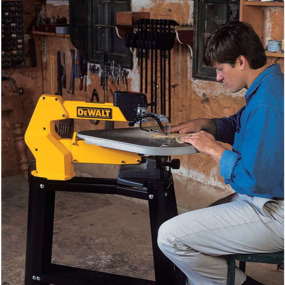 Action shot of a professional woodworker using the DEWALT DW788 20 inch variable speed scroll saw to cut an intricate decorative wooden pattern in a workshop.