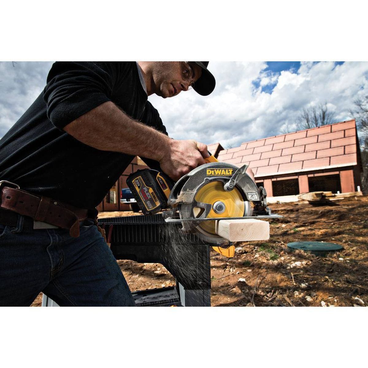 An action lifestyle shot of a professional contractor using a DEWALT FLEXVOLT 60V MAX circular saw with the 24-tooth carbide blade. The image demonstrates a precise cross-cut on a wooden 2x4 stud at an outdoor residential construction site, showcasing the blade's efficiency in structural framing.