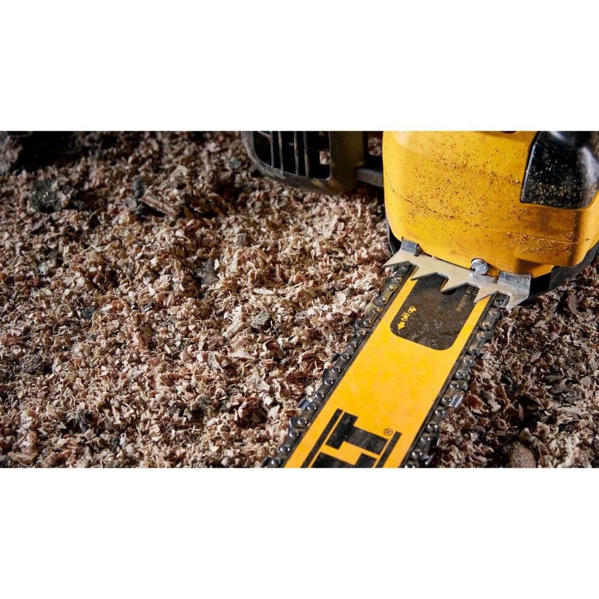 Close-up detail of the DEWALT chainsaw's metal bucking spikes and guide bar resting on a bed of fresh wood chips, demonstrating industrial-grade leverage for log clearing.