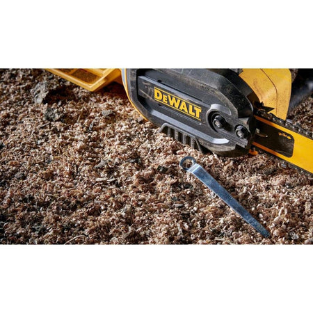 Action detail showing the DEWALT DWCS600 bar retention area and the included multi-tool used for adjusting chain tension amidst heavy wood shavings and jobsite debris.